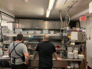 Staff looking at kitchen. Restaurant cleaning services NYC are provided by SanMar building services, a professional kitchen cleaning company in New York City to clean kitchens and exhaust hoods.