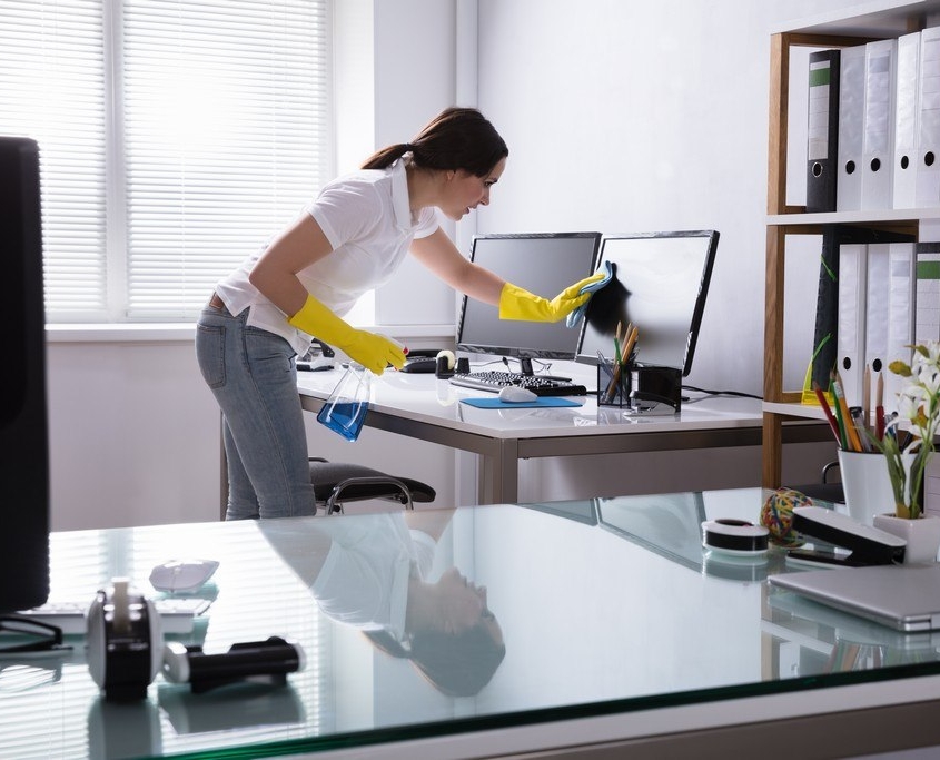 NYC janitorial company, SanMar, employee cleans computer monitors at an commercial business.