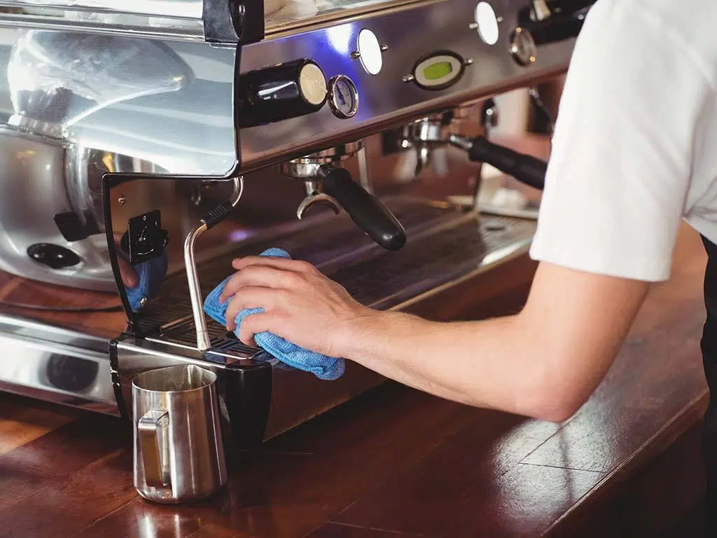 An employee cleaning a coffee machine at a restaurant in New York City.