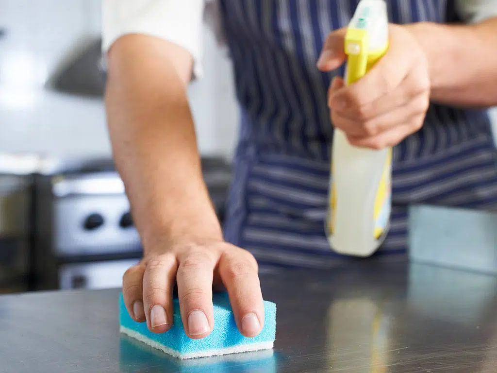 Employee scrubbing surfaces in a kitchen. NYC cleaning services for restaurants.