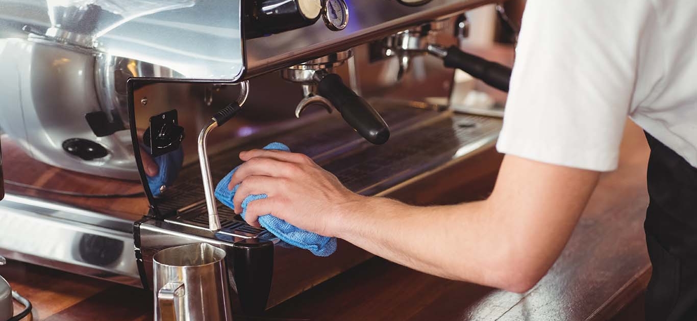 NYC restaurant cleaner wiping down a coffee machine.