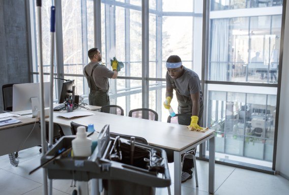 Janitorial service staff wipe down workspaces a commercial office building, New York City.