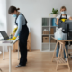 Janitorial staff sanitizing a desktop computer and laptop, demonstrating safe and secure office cleaning practices for businesses.