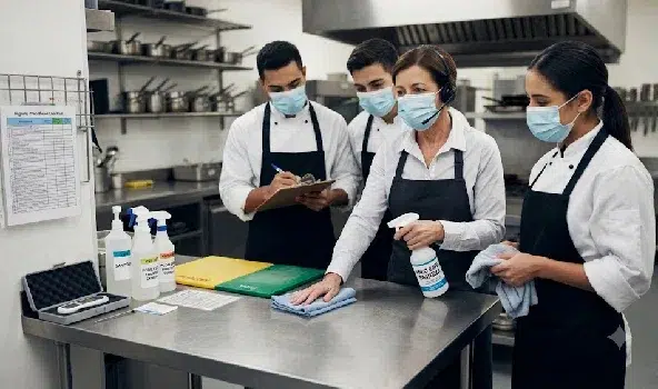 Food establishment manager trains kitchen staff on sanitizing prep counters and verifying daily cleaning checklists and schedules for restaurants in New York City.